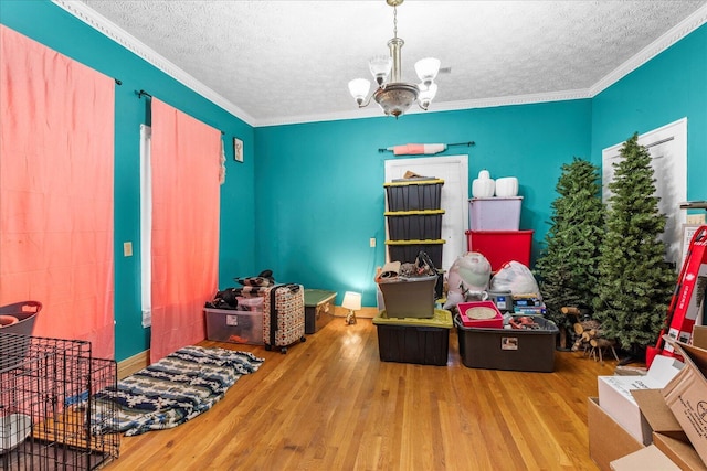 game room featuring crown molding, a chandelier, hardwood / wood-style floors, and a textured ceiling