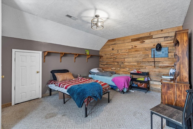 bedroom with vaulted ceiling, wooden walls, light carpet, and a textured ceiling