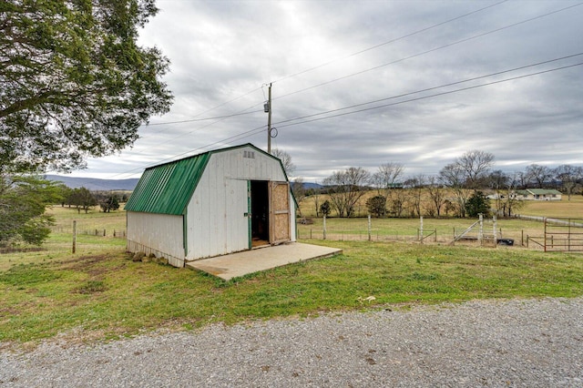 view of outdoor structure with a rural view and a lawn