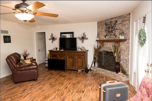 living room with ceiling fan, a fireplace, and hardwood / wood-style floors