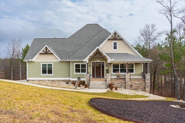 craftsman-style house with a porch, a front yard, and a shingled roof