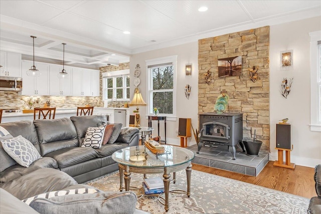 living area with a wood stove, wood finished floors, coffered ceiling, beamed ceiling, and baseboards