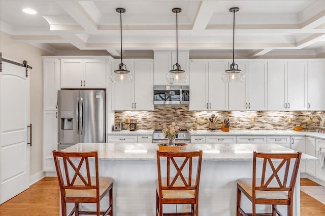 kitchen featuring a barn door, a breakfast bar area, stainless steel appliances, and decorative backsplash