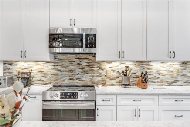 kitchen featuring white cabinetry, appliances with stainless steel finishes, tasteful backsplash, and light stone counters