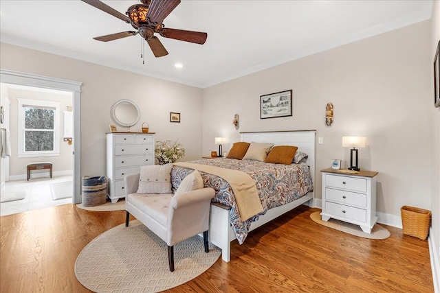 bedroom featuring light wood-type flooring, ceiling fan, baseboards, and ornamental molding