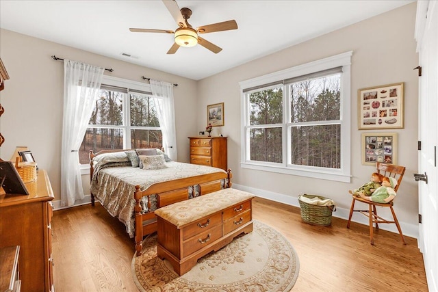 bedroom featuring a ceiling fan, visible vents, baseboards, and wood finished floors