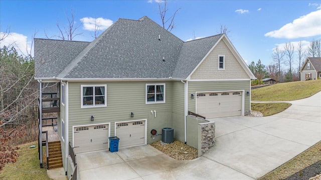 exterior space with driveway, roof with shingles, an attached garage, stairs, and central AC