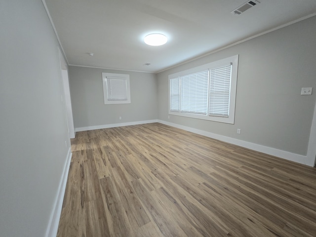 empty room with crown molding and wood-type flooring