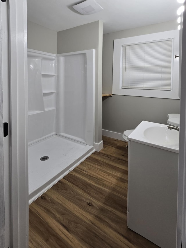 bathroom featuring wood-type flooring, toilet, vanity, and walk in shower