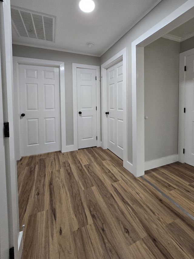 hallway with dark wood-type flooring and ornamental molding