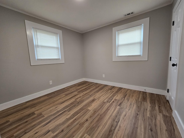 empty room featuring dark hardwood / wood-style flooring, a wealth of natural light, and ornamental molding