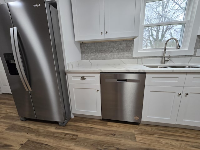 kitchen with sink, appliances with stainless steel finishes, dark hardwood / wood-style flooring, light stone countertops, and white cabinets