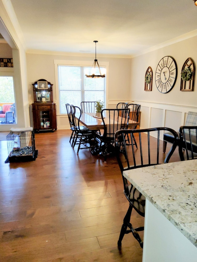 dining space featuring ornamental molding, dark wood-type flooring, and an inviting chandelier