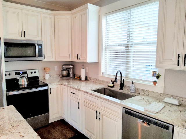 kitchen with white cabinetry, sink, light stone countertops, and appliances with stainless steel finishes