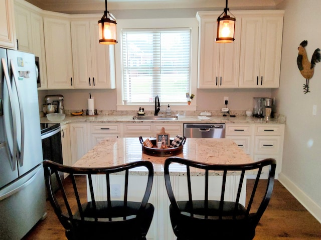 kitchen featuring sink, decorative light fixtures, stainless steel appliances, and a breakfast bar