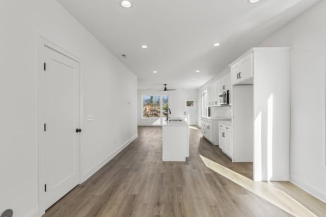 kitchen featuring hardwood / wood-style flooring, decorative backsplash, a kitchen island, and white cabinets