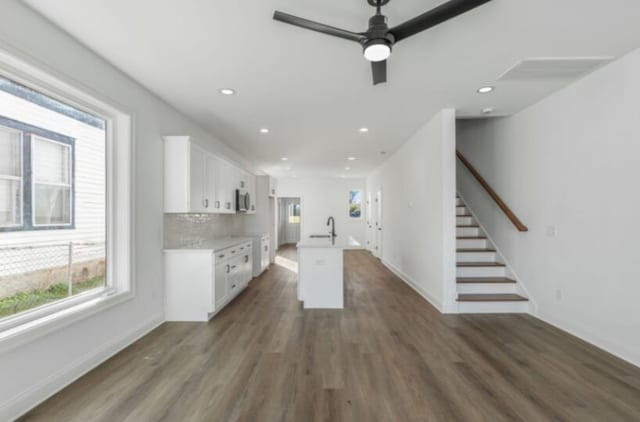 kitchen with sink, dark hardwood / wood-style floors, an island with sink, and white cabinets