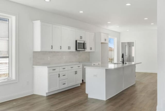 kitchen featuring white cabinetry, a wealth of natural light, an island with sink, and tasteful backsplash