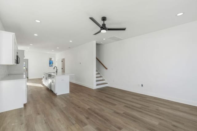 kitchen with sink, white cabinetry, a center island with sink, dark hardwood / wood-style floors, and ceiling fan