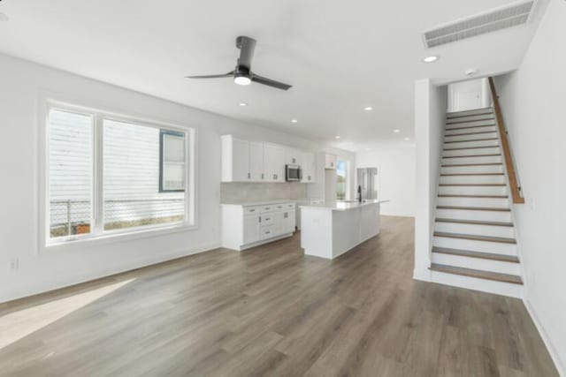 unfurnished living room with ceiling fan and dark hardwood / wood-style flooring