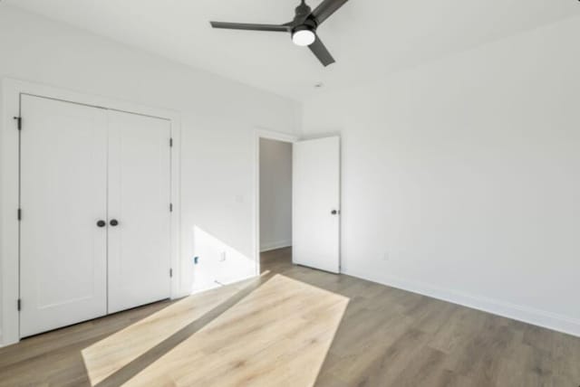 unfurnished bedroom featuring hardwood / wood-style floors, ceiling fan, and a closet