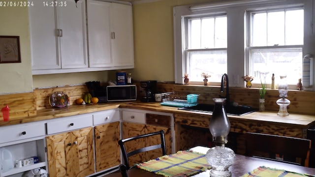 kitchen with sink, white cabinets, and butcher block countertops