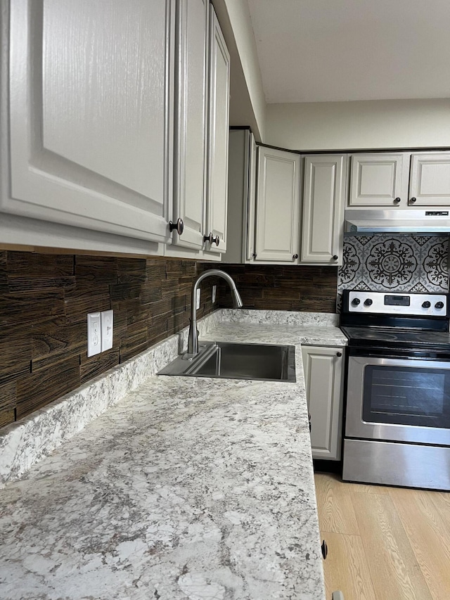 kitchen featuring stainless steel range with electric stovetop, sink, backsplash, and light hardwood / wood-style flooring