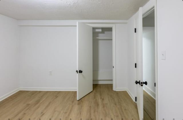 unfurnished bedroom with a textured ceiling and light hardwood / wood-style flooring