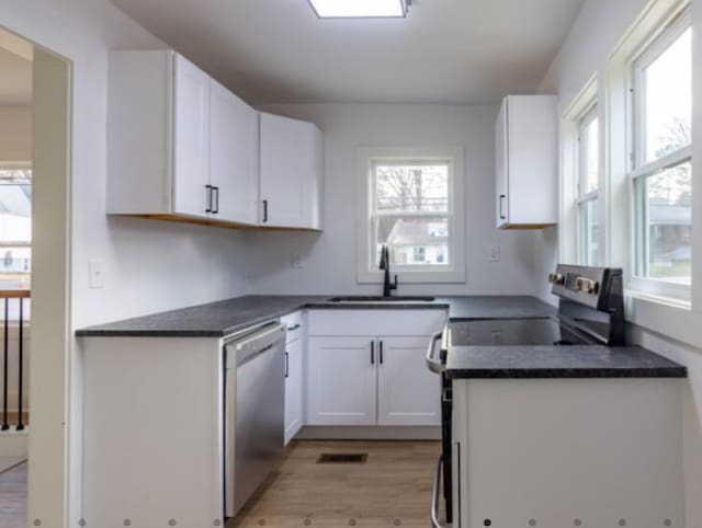 kitchen featuring white cabinetry, sink, light wood-type flooring, and appliances with stainless steel finishes