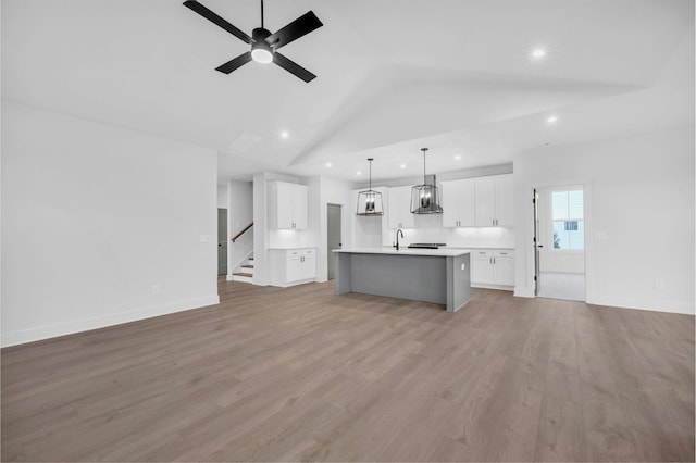 unfurnished living room featuring vaulted ceiling, sink, ceiling fan, and light hardwood / wood-style flooring