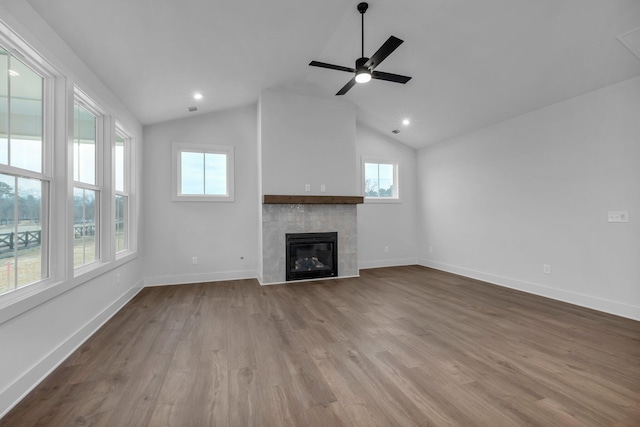 unfurnished living room with a tile fireplace, vaulted ceiling, ceiling fan, and light wood-type flooring