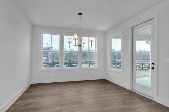 unfurnished dining area featuring an inviting chandelier and wood-type flooring