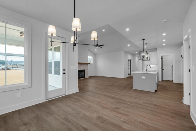 kitchen with sink, hardwood / wood-style flooring, ceiling fan, a kitchen island with sink, and hanging light fixtures