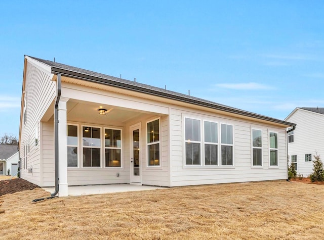 rear view of house with a patio and a lawn