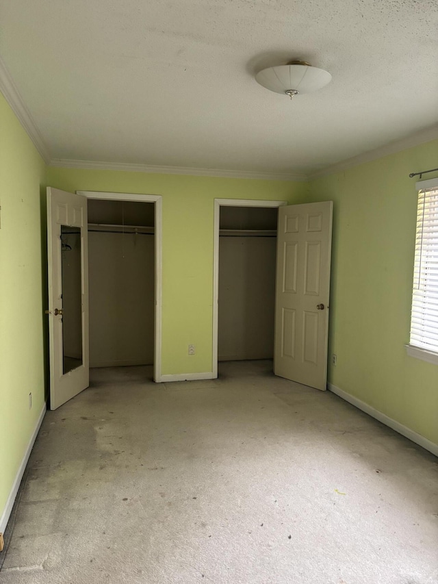 unfurnished bedroom featuring two closets, ornamental molding, and light colored carpet