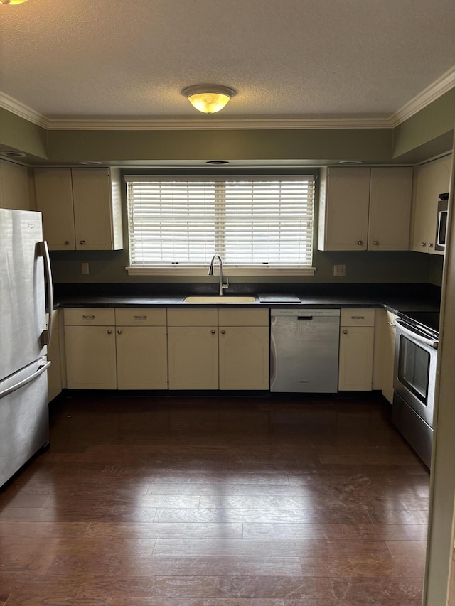 kitchen with sink, ornamental molding, stainless steel appliances, and cream cabinetry