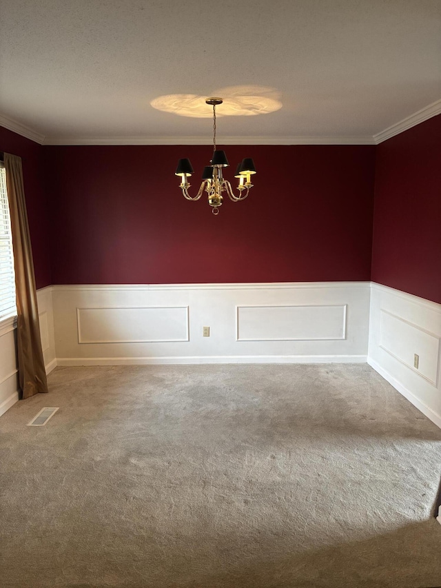 carpeted spare room with an inviting chandelier and ornamental molding