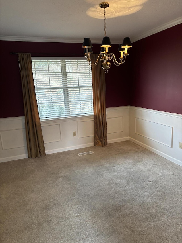 carpeted spare room with ornamental molding and a notable chandelier