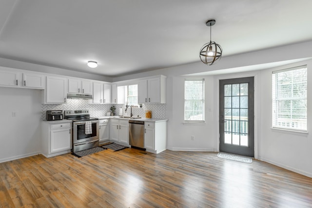 kitchen featuring sink, white cabinetry, hanging light fixtures, appliances with stainless steel finishes, and backsplash