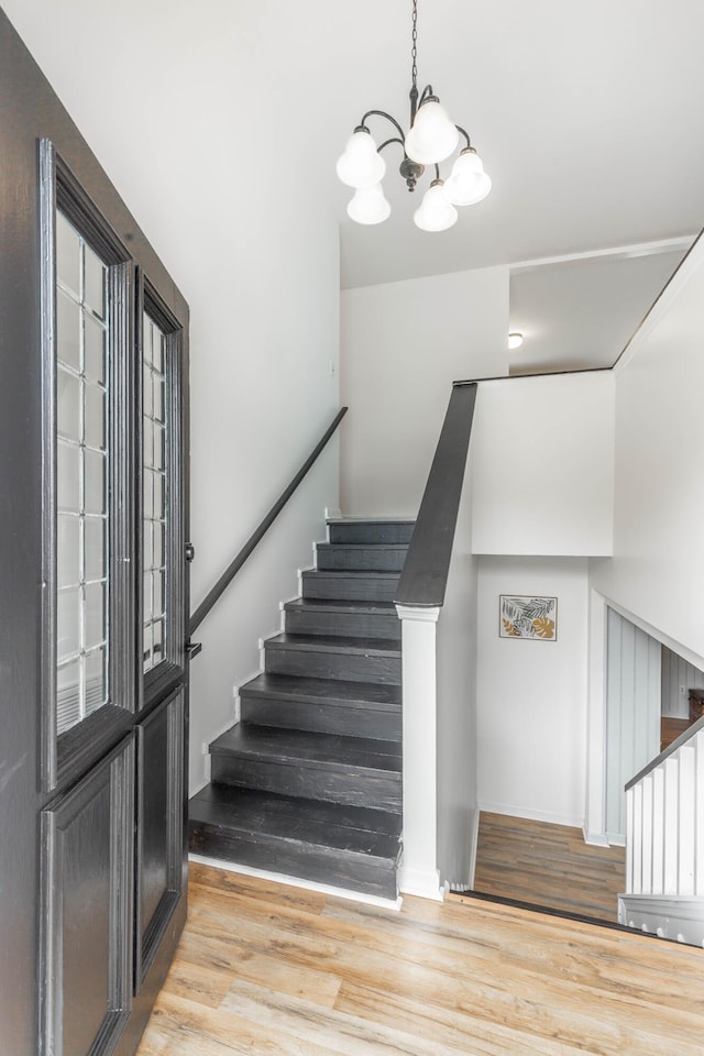 staircase with hardwood / wood-style flooring and a chandelier