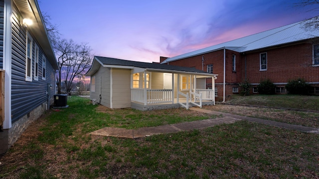 exterior space with a lawn, central air condition unit, and covered porch