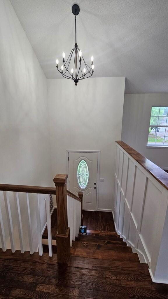 stairs with hardwood / wood-style flooring, a textured ceiling, and an inviting chandelier