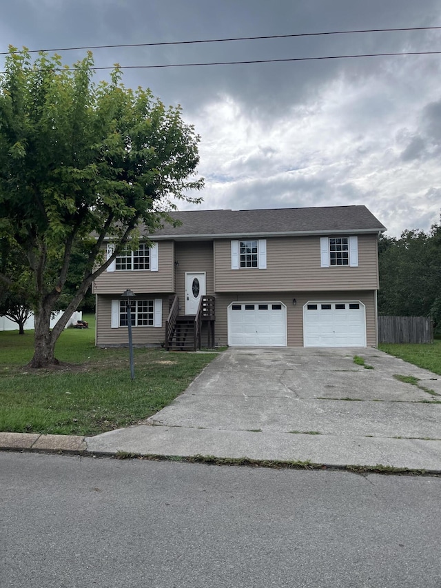 raised ranch featuring a garage and a front lawn