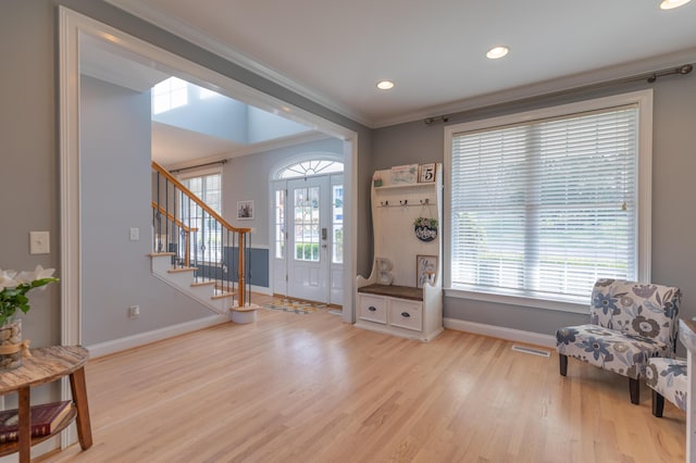 foyer with ornamental molding and light hardwood / wood-style flooring