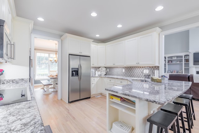 kitchen with white cabinetry, sink, stainless steel appliances, crown molding, and light stone countertops