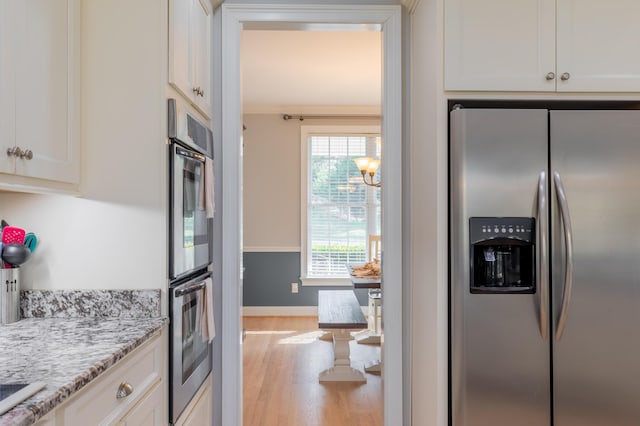 kitchen with light stone counters, light hardwood / wood-style flooring, stainless steel appliances, and white cabinets