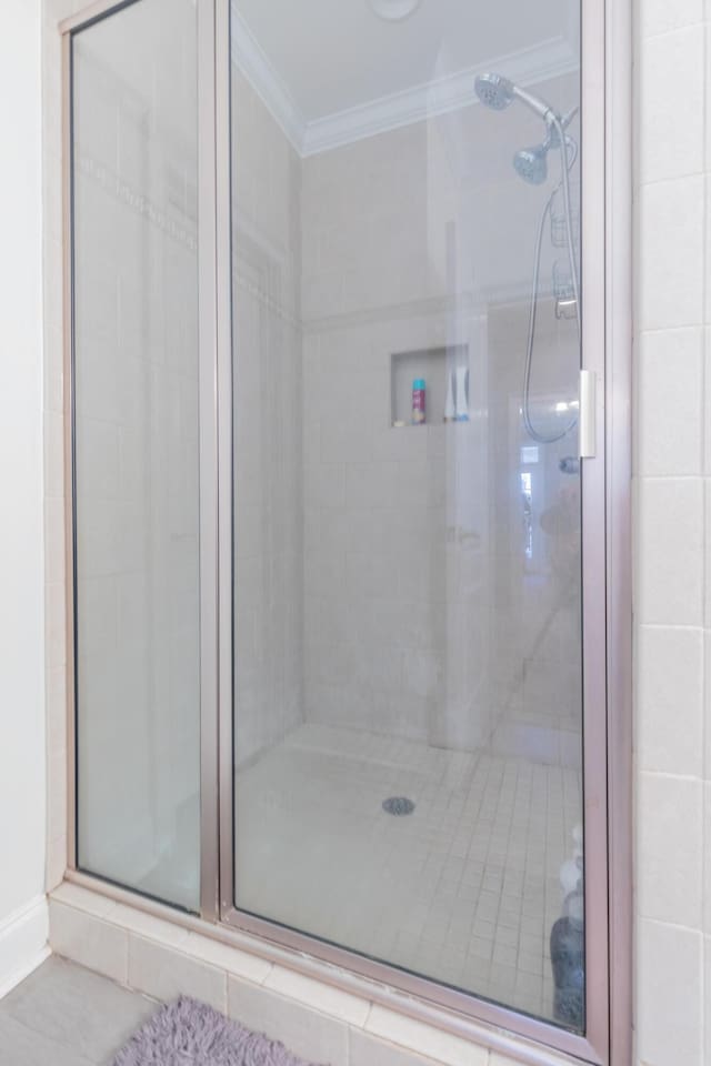 bathroom with ornamental molding and an enclosed shower