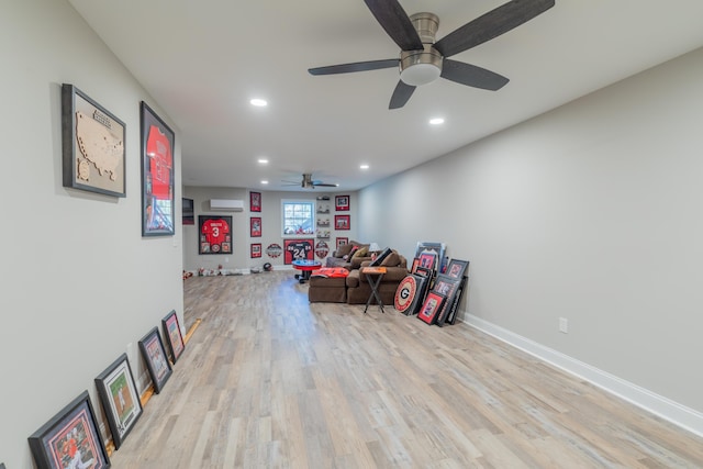 recreation room featuring a wall unit AC and light hardwood / wood-style flooring