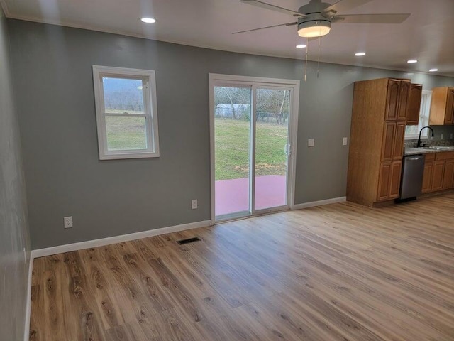 interior space with light wood-type flooring, a healthy amount of sunlight, a sink, and a ceiling fan