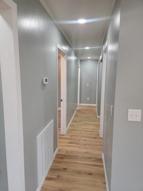corridor with baseboards, recessed lighting, light wood-style flooring, crown molding, and visible vents